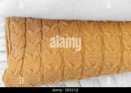 Nahaufnahme warmer Strickpullover in Pastellfarben und Beige, ordentlich gestapelt. Stockfoto