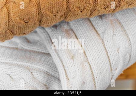 Nahaufnahme warmer Strickpullover in Pastellfarben und Beige, ordentlich gestapelt. Stockfoto