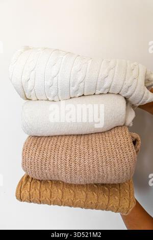 Nahaufnahme warmer Strickpullover in Pastellfarben und Beige, ordentlich gestapelt. Stockfoto