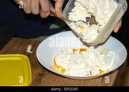 Hüttenkäse und Eier in einem Teller mischen, Piroski füllen Stockfoto