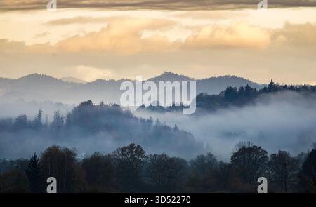 neblige Herbsthügel mit mehrschichtigem Nebel und dramatischen Wolken Stockfoto