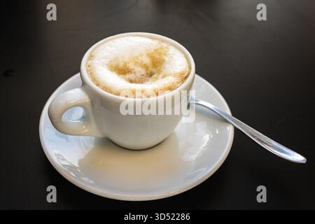 Tasse Cappuccino oder Latte mit schaumigem Milchschaum auf Untertasse Stockfoto