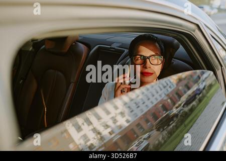 Porträt einer Frau mittleren Alters, die beim Telefonieren im Auto lächelt Stockfoto