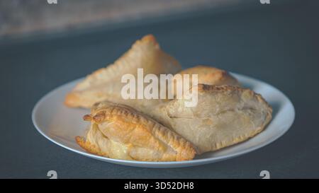 Eine Menge hausgemachter Blätterteiggebäck mit knusprigen, goldenen Schichten ruhen auf einer rustikalen Holzoberfläche in einer warmen Küche, die das einladende Aroma und einfängt Stockfoto