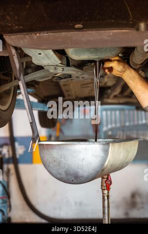 Manuelles Ablassen von gebrauchtem Motoröl aus einem Pkw-Motor bei Wartungsarbeiten Stockfoto