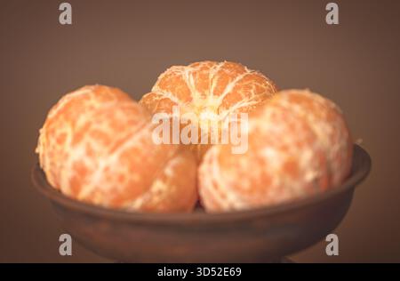 Geschälte Mandarinensegmente in einer Tonschale auf einem Tisch, helle goldorange Früchte mit natürlichem Licht Stockfoto