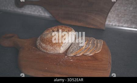 Geschnittene Stücke von dunklem Buchweizenbrot liegen auf einem Holzschneidebrett, warmes natürliches Licht hebt die körnige Textur hervor Stockfoto