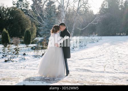 Eine Winterhochzeit, der Bräutigam im Smoking und die Braut in einem weißen Hochzeitskleid Stockfoto