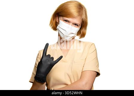 Eine Ärztin, eine Angestellte im Gesundheitswesen. Sie macht das STEINZEICHEN, während sie einen schwarzen Handschuh trägt. Ihr Zeigefinger und ihr kleiner Finger sind gerade. Das ist sie Stockfoto
