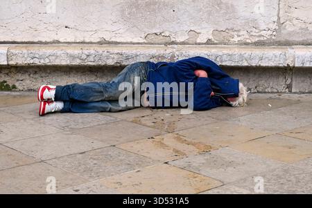 Mann, der auf dem Boden schläft in der Stadt, Frankreich, konzeptuelles Sozialbild Stockfoto