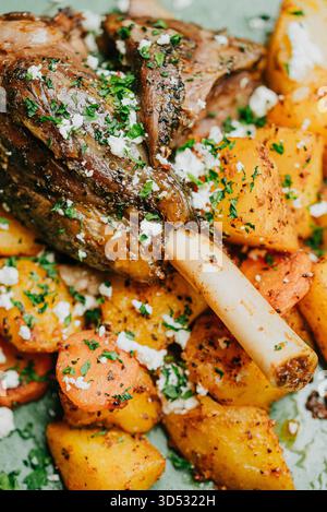 Ein Teller mit Fleisch und Gemüse, einschließlich Karotten und Kartoffeln. Das Fleisch ist gewürzt und hat viel Geschmack Stockfoto