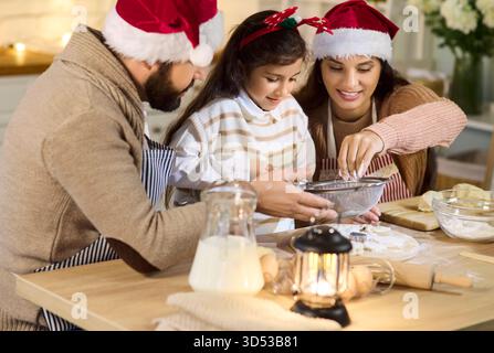 Fröhliche Familie, die Weihnachtskekse zu Hause in gemütlicher Weihnachtsküche backen kann Stockfoto