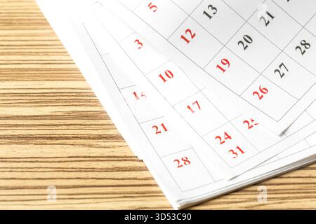 Nahaufnahme eines Kalenders mit Datumsangaben und einem hölzernen Tischhintergrund Stockfoto