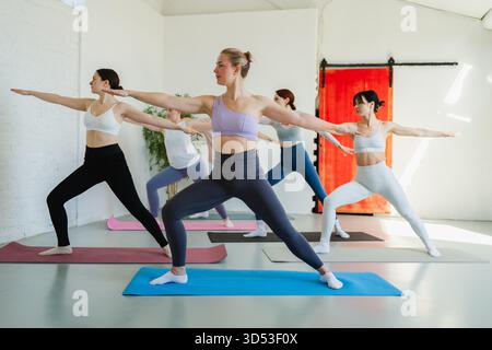 Yoga-Kurs Pilates Workout. Gruppe sportlicher Menschen, die im Studiounterricht Sport treiben, um Yoga Wellness Achtsamkeitsmeditation zu praktizieren. Personal Trainer Männer Frauen üben Yoga im Gym Training dehnen innen Stockfoto