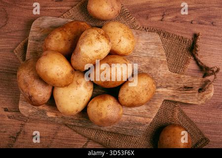 Rohe Kartoffeln, verstreut auf einem Schneidebrett, Nahaufnahme, keine Leute, Stockfoto