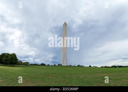 Das Washington Monument mitten auf einem Feld. Der Himmel ist bewölkt und das Gras ist grün. Washington, D.C. Stockfoto