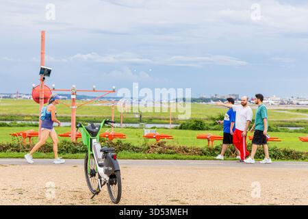 Eine Gruppe von Menschen läuft in Gravelly Point, Washington, mit einem grünen Fahrrad im Hintergrund. Die Szene ist entspannt und gemächlich, so wie die Menschen es sind Stockfoto