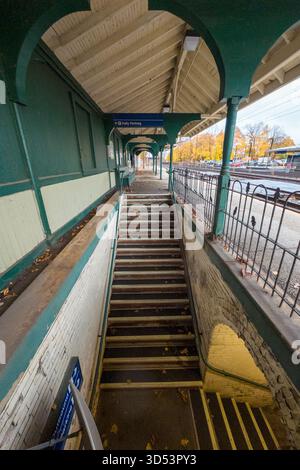 Bahnhof Devon. Eine lange Treppe führt zu einem Bahnsteig mit blauem Schild. Die Treppe ist leer und die Plattform ist leer Stockfoto