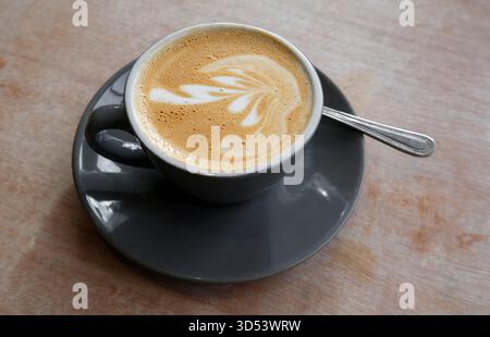 Cortado-Kaffee in dunkelgrauer Tasse und Untertasse auf Holztisch, norfolk, england Stockfoto