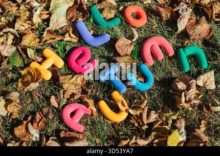 Hello Herbstnachricht aus mehrfarbigen Tonbuchstaben zwischen Herbstlaub auf einem Rasen Stockfoto