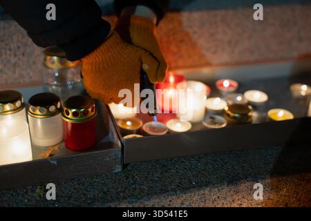 Nahaufnahme einer Person, die Kerzen auf der Krastmala-Treppe mit einem Taschenlampen anzündet, die warme leuchtende Laternen, strukturierte Steinflächen und ein zeigen Stockfoto