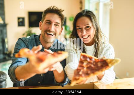 Ein liebevolles Paar teilt einen zärtlichen Moment in der modernen Küche und genießt Pizza Stockfoto