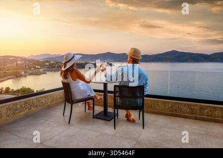 Ein elegantes Urlaubspaar genießt den schönen Sommeruntergang im mittelmeer mit einem Glas Wein, romantischem Flitterwochen-Urlaubskonzept Stockfoto