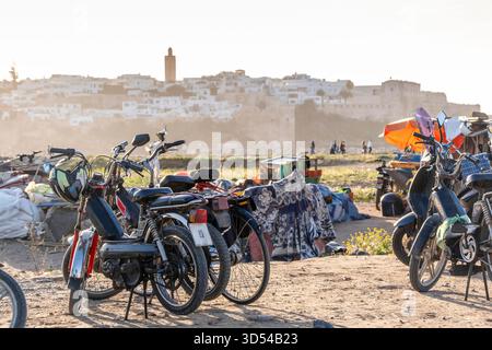 Rabat, Marokko – geparkte Motorräder und Motorroller in der Nähe des Strandes mit der historischen Kasbah der Udayas und der alten Medina, die im Hintergrund sichtbar ist Stockfoto