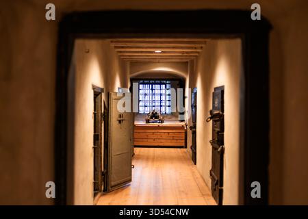 Eine Gefängniszelle aus Stein in einer alten mittelalterlichen Burg, rostige Metallstäbe und dunkles Licht schaffen eine dunkle historische Atmosphäre. Symbol der mittelalterlichen Gerechtigkeit und Stockfoto