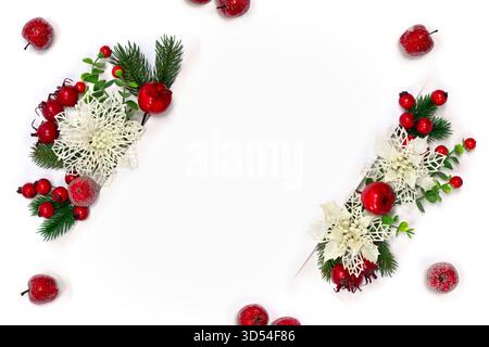 Weihnachtsdekoration. Zweige Сhristmas des Baumes, rote Beeren, rote Äpfel, weiße durchbrochene Blumen mit weißer Papierkarte mit Platz für Text Stockfoto