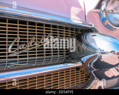 Eine Nahaufnahme des bekannten und vertrauten Kühlergrills und Firmenschrift eines restaurierten Vintage-pinken Coupe de Ville aus dem Jahr 1956 Cadillac Series 62 Stockfoto