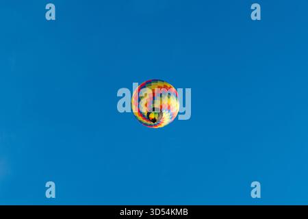 Farbenfroher Heißluftballon, der im klaren blauen Himmel schwimmt Stockfoto