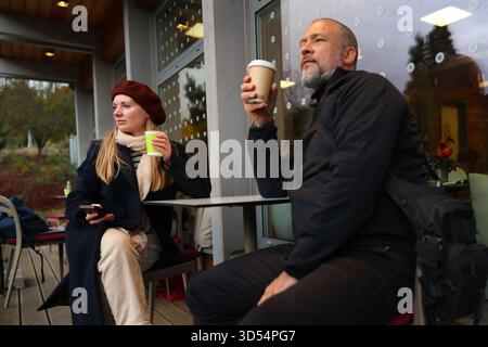 Paare genießen heiße Getränke in einem Café im Freien im Herbst, warm gekleidet und entspannt zusammen. Gemütliches Lifestyle- und Freizeitkonzept. Stockfoto