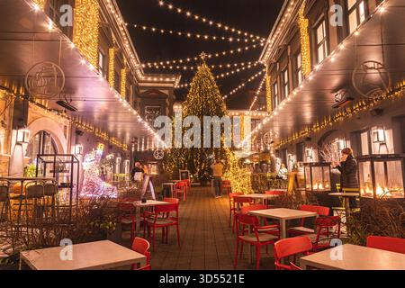 Festlich eingerichteter Innenhof in der Altstadt von Vilnius mit einem Weihnachtsbaum, leuchtenden Lichtern und gemütlichen Cafés im Freien schaffen ein warmes Ambiente Stockfoto
