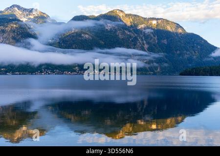 Nebelige Berge spiegeln sich im ruhigen Wasser des Hallstätter Sees, Österreich Stockfoto