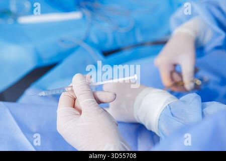 Nahaufnahme einer Handschuh-Handspritze mit Narkose bei sterilen chirurgischen Eingriffen im modernen Krankenhausoperationssaal Stockfoto