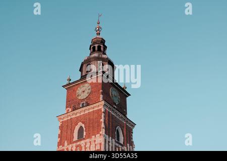 Historischer Uhrenturm des Rathauses in Kraków, fotografiert bei Sonnenuntergang mit klarem blauem Himmel. Stockfoto