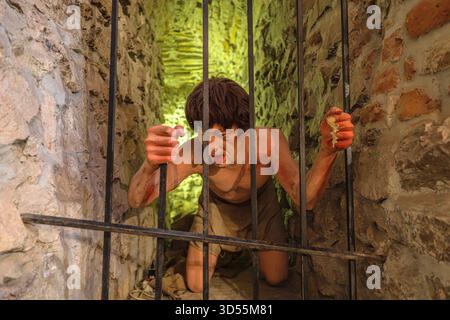 Transsilvanien, Rumänien - 8. Oktober 2025: Wachsfigur der Gefangenen hinter Eisenstäben, die Folter und Gefangenschaft in der historischen Folterkammer des Häftlings repräsentiert Stockfoto