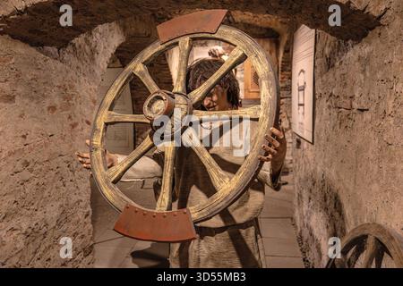 Transsilvanien, Rumänien - 8. Oktober 2025: Schaufensterpuppe in einem historischen Kostüm mit einem Brechen-Rad im Museum der Folterkammer in der Burg Corvin Stockfoto