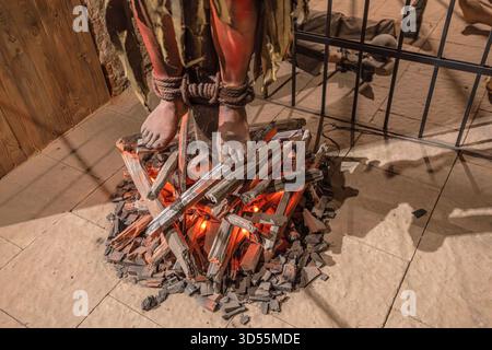 Transsilvanien, Rumänien - 8. Oktober 2025: Museumsausstellung mit mittelalterlichen Foltermethoden, mit Schaufensterfüßen, die über simuliertes brennendes Holz gebunden sind Stockfoto