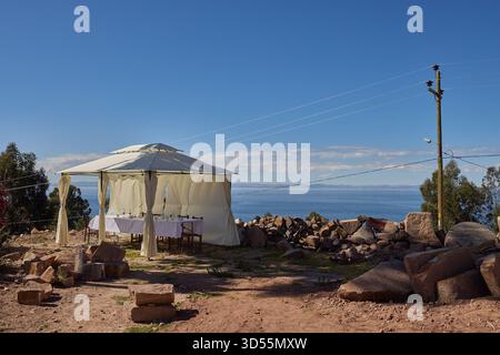 Mittagessen am Himmelsrand. Ein ruhiger Tisch mit Blick auf das tiefe Blau des Titicacasees, wo die Zeit langsamer wird und die Welt sich endlos anfühlt Stockfoto