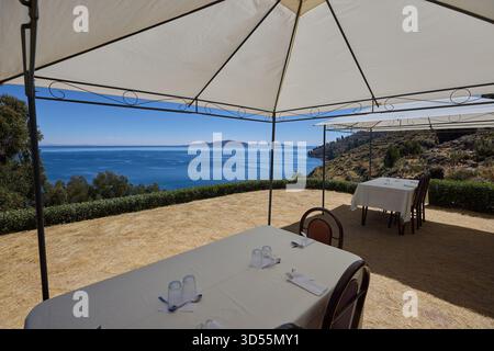 Mittagessen am Himmelsrand. Ein ruhiger Tisch mit Blick auf das tiefe Blau des Titicacasees, wo die Zeit langsamer wird und die Welt sich endlos anfühlt Stockfoto