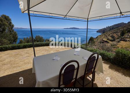 Mittagessen am Himmelsrand. Ein ruhiger Tisch mit Blick auf das tiefe Blau des Titicacasees, wo die Zeit langsamer wird und die Welt sich endlos anfühlt Stockfoto