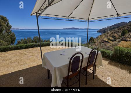 Mittagessen am Himmelsrand. Ein ruhiger Tisch mit Blick auf das tiefe Blau des Titicacasees, wo die Zeit langsamer wird und die Welt sich endlos anfühlt Stockfoto