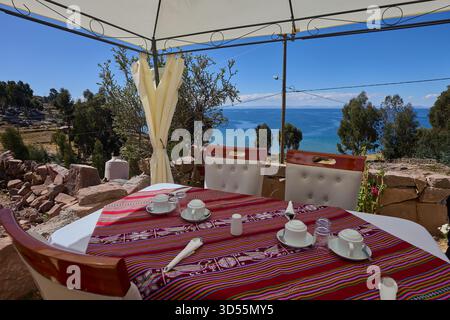 Mittagessen am Himmelsrand. Ein ruhiger Tisch mit Blick auf das tiefe Blau des Titicacasees, wo die Zeit langsamer wird und die Welt sich endlos anfühlt Stockfoto