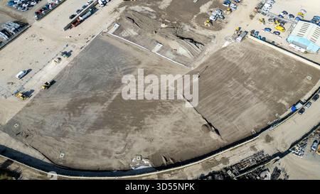 Aus der Vogelperspektive auf eine große Baustelle mit Schotterpfählen, schweren Maschinen, Fahrzeugen und einem lagerähnlichen Gebäude in Copart Yard, York, Großbritannien. Stockfoto