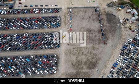 Ein Blick aus der Luft zeigt einen großen Außenbereich mit zahlreichen geparkten Autos. Die Fahrzeuge sind in Reihen und Abschnitten angeordnet, wobei einige Abschnitte gewidmet sind Stockfoto
