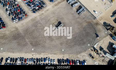 Aus der Vogelperspektive auf einem riesigen Asphaltgelände mit geparkten Autos und einigen schweren Maschinen in Copart Yard, York, Großbritannien. Stockfoto