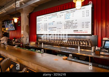 Dieses lebhafte Restaurant in Cleveland, Ohio, bietet eine große Auswahl an Craft-Bieren vom Fass, die an prominenter Stelle auf einer digitalen Tafel gezeigt werden. Die Stockfoto