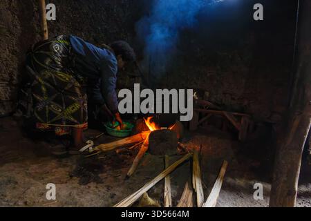 Gasura Ruanda - 8. September 2025; authentisches afrikanisches Dorf Leben Woman bändigt sich über das Waschen von Speisen in einer grünen Schüssel, bevor es in Feuer gesetzt wird, um in tra zu kochen Stockfoto